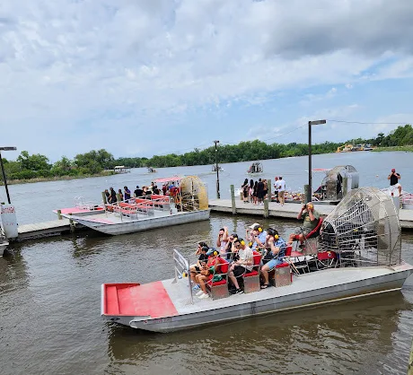 Several airboats are docked at the swamp tour launch as tourists board, reflecting the bustling start of a New Orleans swamp tour adventure.